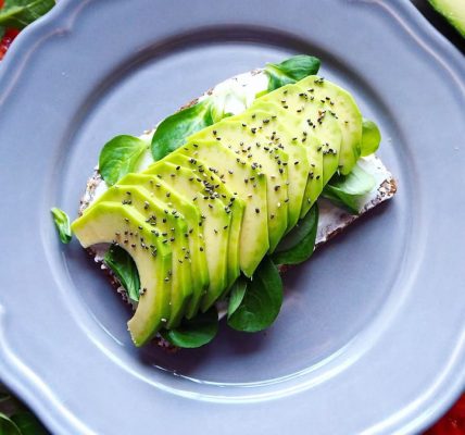 Delicious avocado toast with chia seeds and fresh tomatoes on a grey plate.