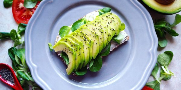 Delicious avocado toast with chia seeds and fresh tomatoes on a grey plate.