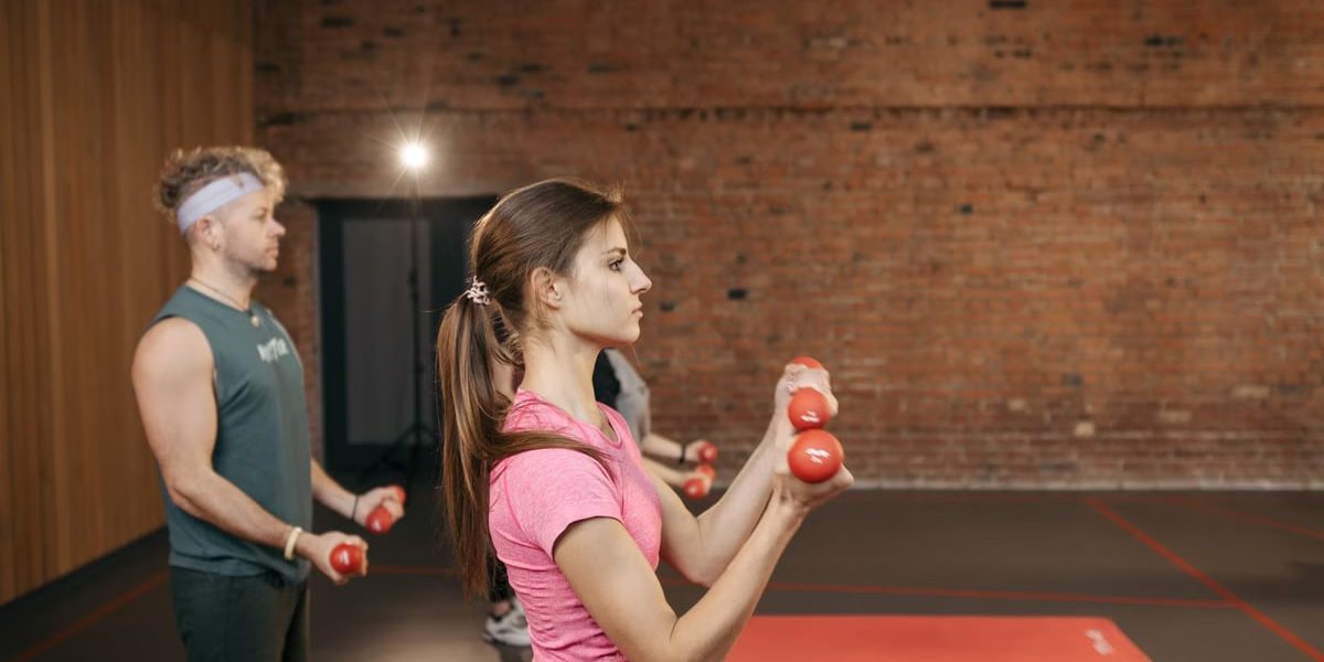 Group of adults exercising indoors with dumbbells, focused on fitness and health.