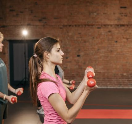 Group of adults exercising indoors with dumbbells, focused on fitness and health.