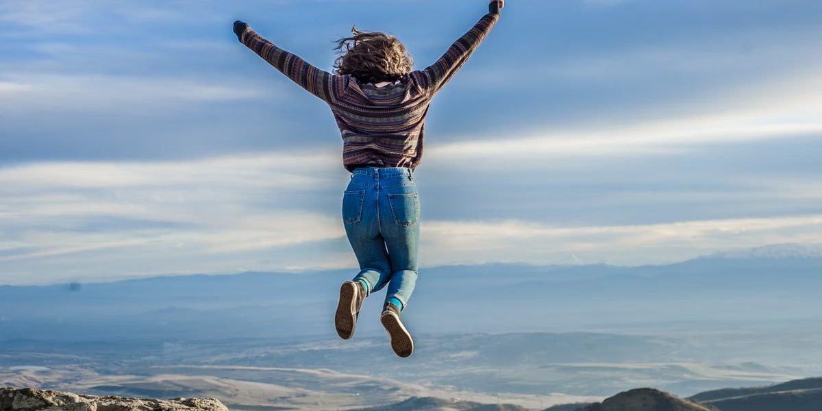 Person jumping on a mountain peak, celebrating adventure and freedom.