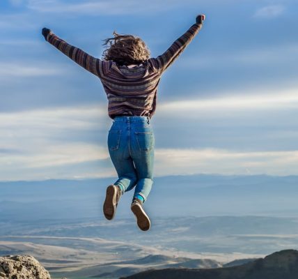 Person jumping on a mountain peak, celebrating adventure and freedom.