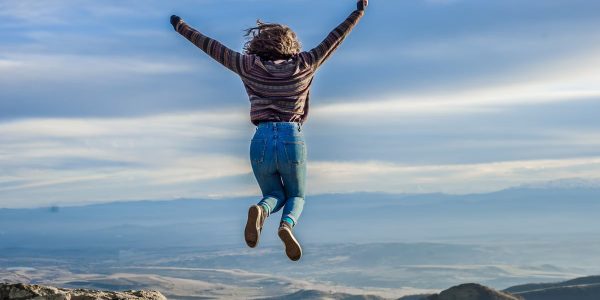 Person jumping on a mountain peak, celebrating adventure and freedom.